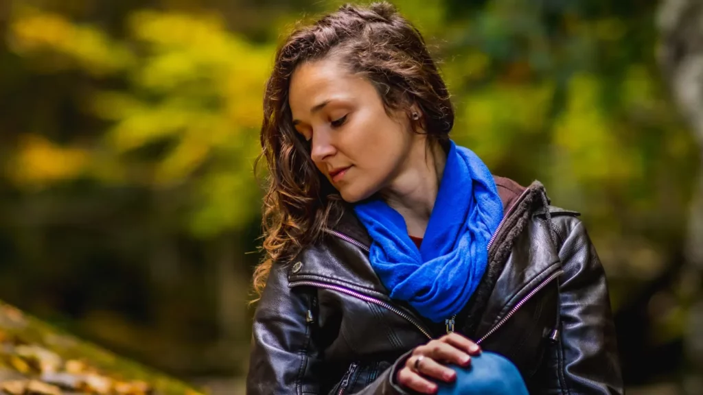 women with curly brown hair and leather jacket looking down